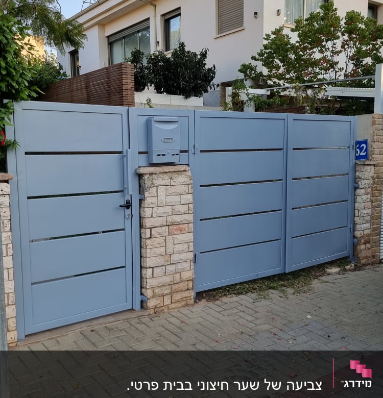 שער מתכת כחול עם תיבת דואר על עמוד אבן